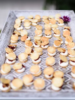 Bandeja de plata labrada con bocados de galleta crujiente rellenos de crema de queso, servidos en un cóctel de boda